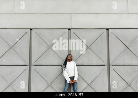 Young woman holding a tablet at a grey wall Stock Photo