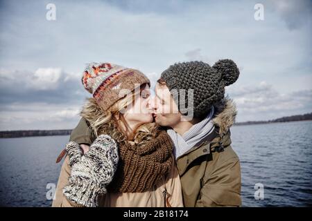 Young couple kissing in front of a lake Stock Photo