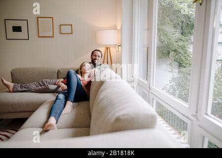 Couple sitting at home on couch, relaxing Stock Photo