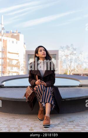 Young woman with smartphone resting in the city Stock Photo