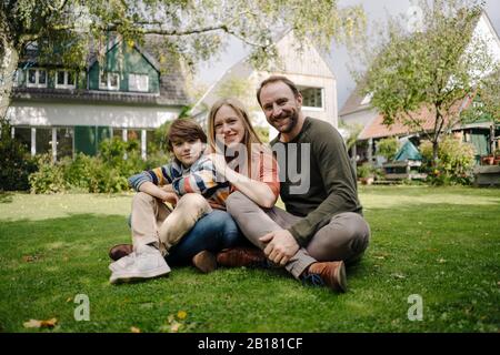 Happy family sitting on grass in their garden Stock Photo