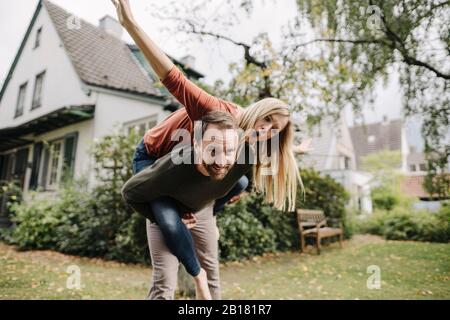 Cheering couple pretending to fly, standing in their garden Stock Photo