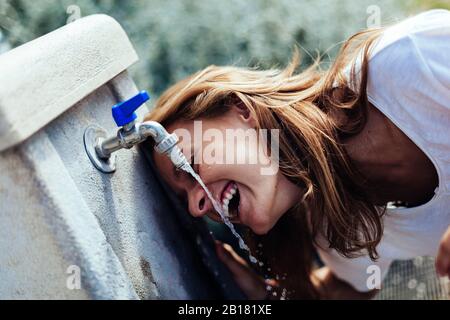 Happy teenage girl drinking water from a well Stock Photo