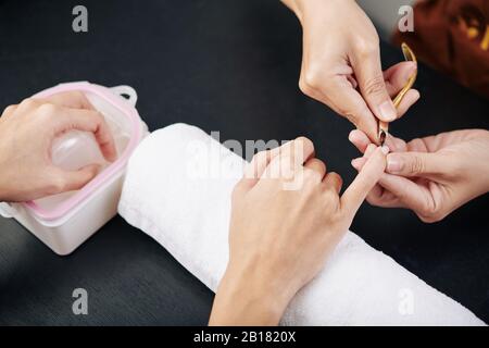 Close-up image of manicurist cutting cuticle on hand of female client, view from above Stock Photo