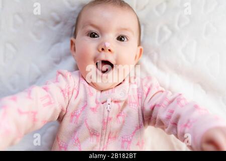 Portrait of baby girl with pink heart-shaped candy on nose Stock Photo