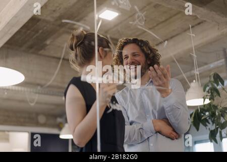 Smiling businessman and businesswoman working on a project in office Stock Photo