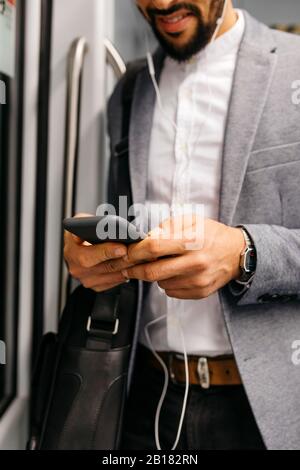 Close-up of businessman using cell phone on the subway Stock Photo