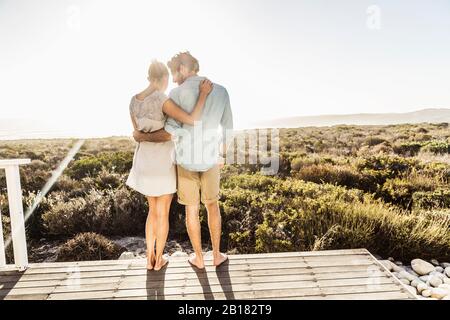 Affectionate young couple embracing on terrace at the coast in summer Stock Photo