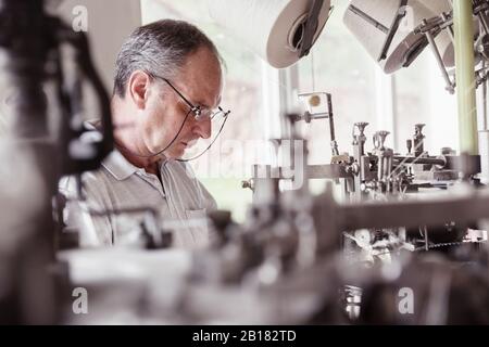 Man working at a machine in a textile factory Stock Photo