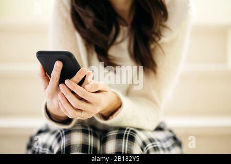 Close-up of woman sitting on stairs holding cell phone Stock Photo