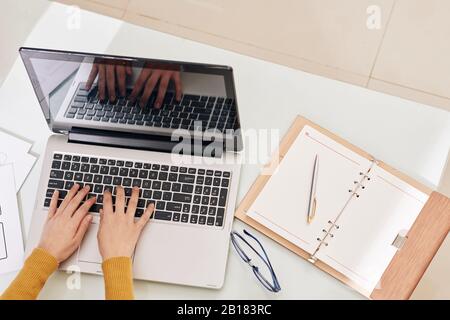 Hands of female back end developer working on laptop with her opened planner near by Stock Photo