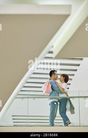 Happy young couple hugging and looking at each other after shopping in mall on weekend Stock Photo