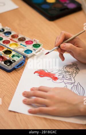 Girl paints a coloring book for adults with crayons Stock Photo