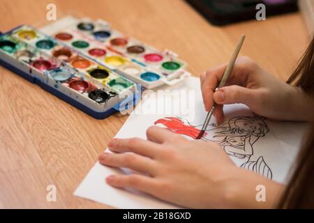Girl paints a coloring book for adults with crayons Stock Photo