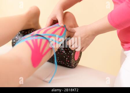 Physical therapist applying kinesio tape on female patient's calf. Kinesiology, physical therapy, rehabilitation concept. Close up. Stock Photo