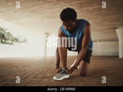 Sportsman tying shoelace and getting ready for fitness on city street Stock Photo