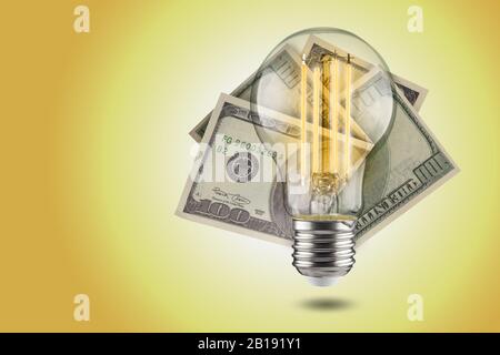 Energy saving concept. LED light bulb with dollars on a yellow background. Stock Photo