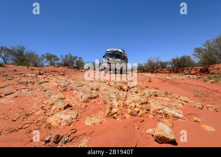 4 Wheel Drive Toyota Coaster driving off road along a red dirt road