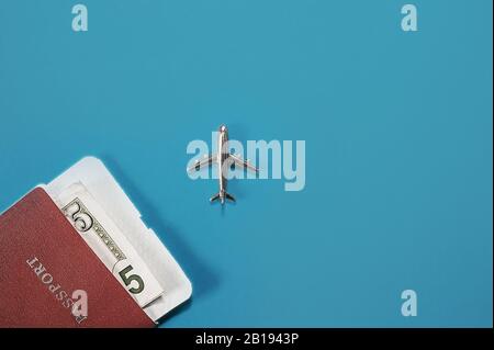 Ready-made layout for tourism and travel by plane. Passport and cash in dollars, metal figurine of a fake plane. Flatlay, top view, layout Stock Photo