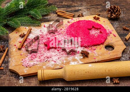 Cooking red ginger cookies. Traditional Christmas pastries. Festive culinary background. Fir tree, spices, cookie cutters, raw dough, rolling pin, woo Stock Photo