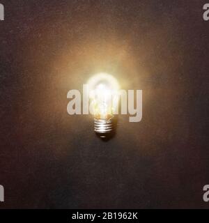 Glowing light bulb. Realistic image of included tungsten light bulb on gray background, top view. Creative idea concept Stock Photo