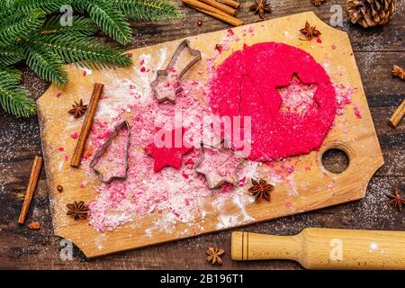 Cooking red ginger cookies. Traditional Christmas pastries. Festive culinary background. Fir tree, spices, cookie cutters, raw dough, rolling pin, woo Stock Photo