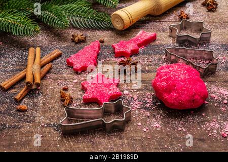 Cooking red ginger cookies. Traditional Christmas pastries. Festive culinary background. Fir tree, spices, cookie cutters, raw dough, rolling pin, woo Stock Photo