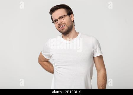 Exhausted young man suffering from back pain, muscle inflammation. Stock Photo
