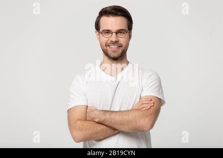 Happy millennial confident man in glasses standing with folded hands. Stock Photo