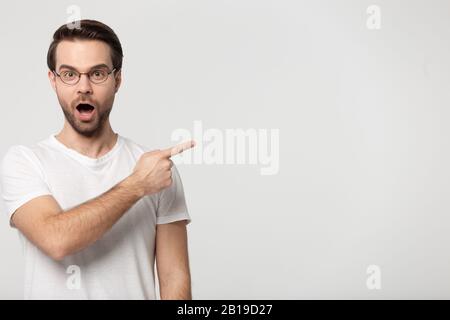 Excited young guy pointing finger aside on empty free space. Stock Photo