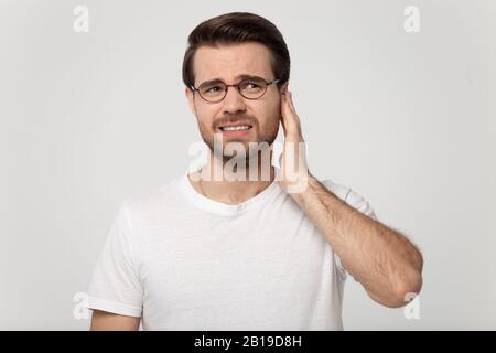 Unhealthy young man suffering from sudden throbbing ear ache, Stock Photo