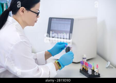 Technician in blue gloves holding samples with blood Stock Photo