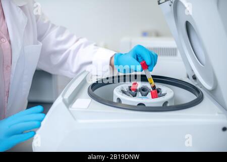 Close up of human hand putting the test tube to centrifuge Stock Photo