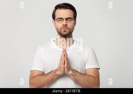 Hopeful young man in glasses praying to God. Stock Photo