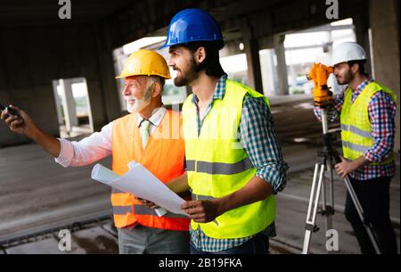 Two satisfied engineers talking at building site with construction structure in background Stock Photo