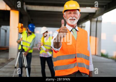 Two satisfied engineers talking at building site with construction structure in background Stock Photo