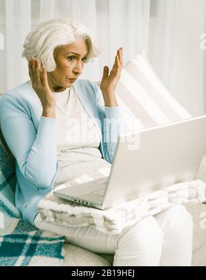 Elderly Woman Communicating In Social Network. Pretty Woman Using Laptop Computer While Staying At Home. Computer Technologies Concept. Stock Photo