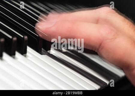 Hand moving fast over notes or keys on a piano or synthesizer keyboard playing music quickly, showing motion blur. Musician concept. Stock Photo