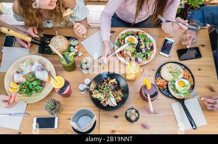 Top view of young people eating brunch and drinking smoothie bowl at  vintage bar - Students having a lunch and chatting in trendy restaurant - Food t Stock Photo