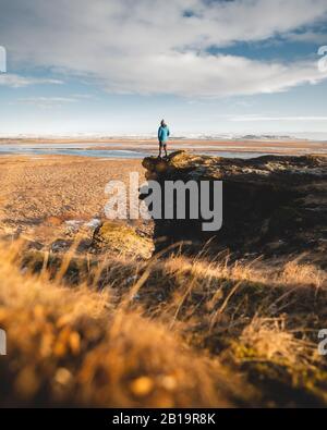 A young posing adventurous guy in a landscape of Iceland during the golden hour. Bucket list and Tourism in Iceland is worth your visit. Beautiful Stock Photo