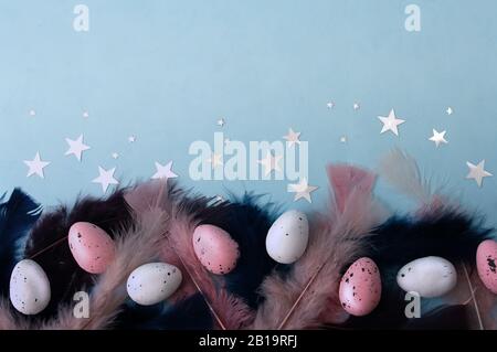 Flat lay easter eggs with dark blue, pink feather on mint color backdrop, silver stars. Place for text. Greeting card design. Stock Photo