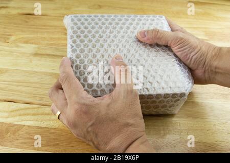 hand of man hold Bubbles covering the box by bubble wrap for protection product cracked  or insurance During transit - Stock Photo