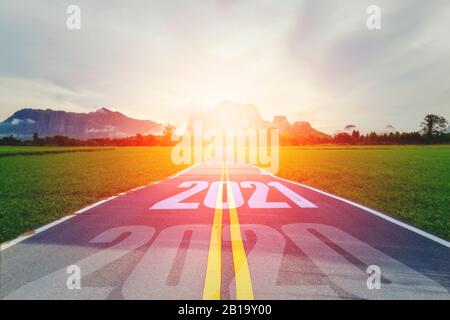 Concept new year With The word 2020 to 2021 Written on The asphalt  road in country road Decorate orange light for beauty With With views of rice fiel Stock Photo