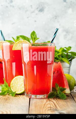 Watermelon slushie with lime and mint, summer refreshing drink in tall glasses on a light blue background. Sweet cold smoothie Stock Photo