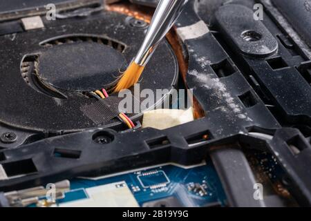 Cleaning a dirty, dusty laptop inside with a brush. Stock Photo