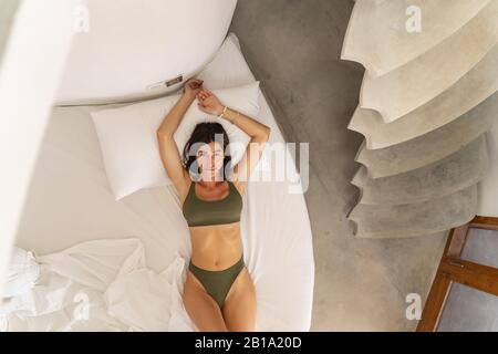 Calm fit young lady relaxing in bed Stock Photo