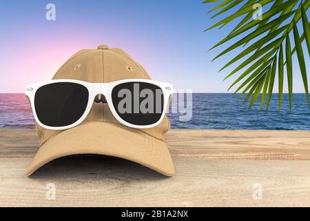 Summer vacation. A baseball cap with glasses against the sea. Stock Photo