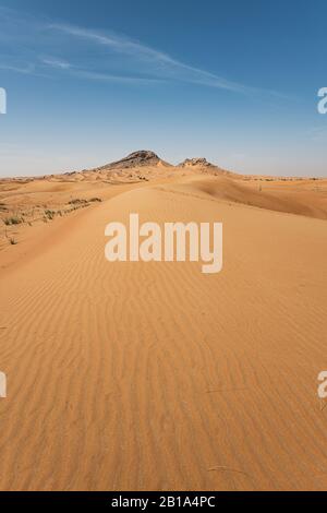 Sand Dunes vertical landscape with Mountains in the background, blue sky and with large copy space for text Stock Photo