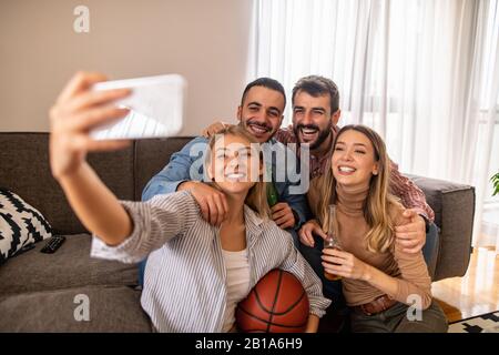 Group of friends watching sport together.Very excited friends having fun at home, watching basketball.Friendship,leasure,people and home party concept Stock Photo