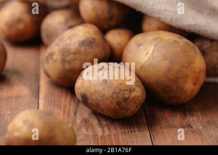 Close up of raw fresh organic potatoes on wooden table Stock Photo